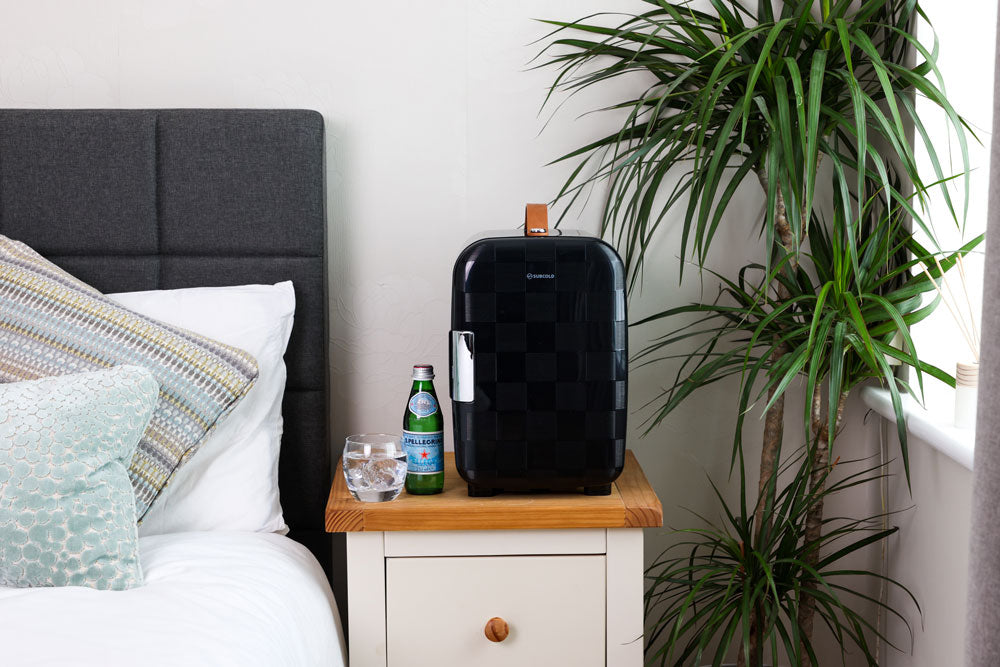 Subcold Pro 10L mini fridge on a bedside table, black body with brown handle