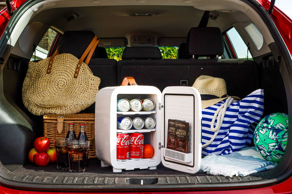 White mini fridge placed in a car trunk with groceries and drinks