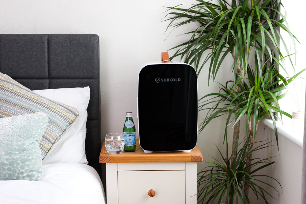 Portable mini fridge with black front and white body, standing upright on a cabinet
