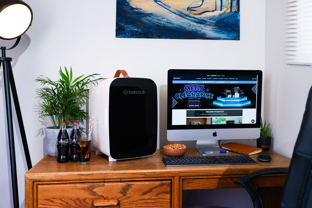 Portable mini fridge with black door and white body on a desk setup