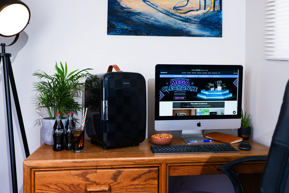Black mini fridge on a desk in an office setting, with drinks inside