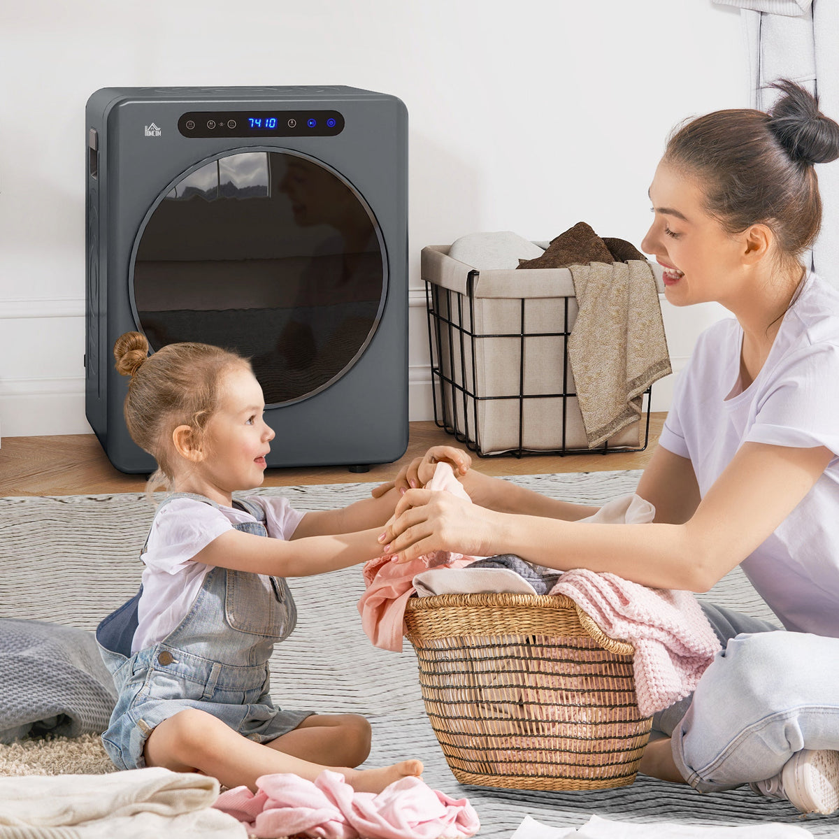Grey compact tumble dryer with open door while folding laundry
