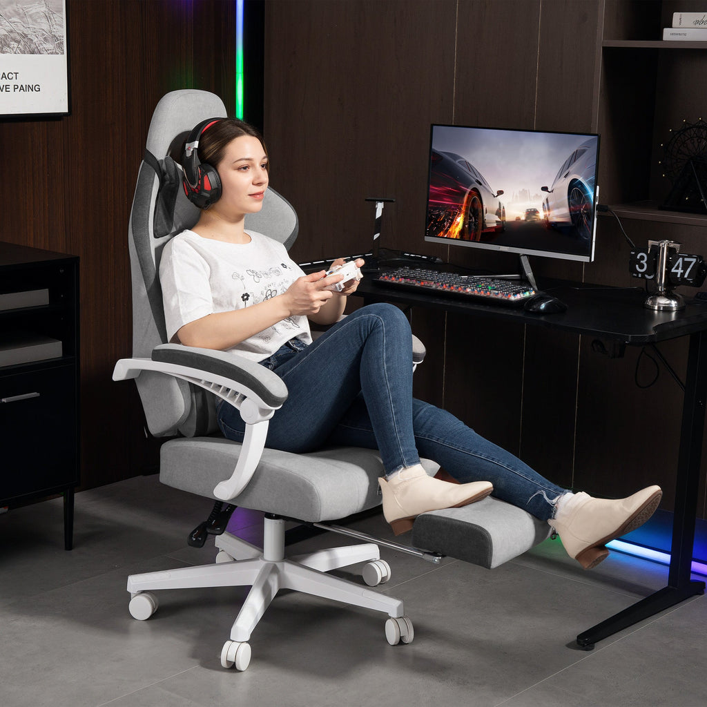 Grey high-back office gaming chair with headrest and footrest, shown in use