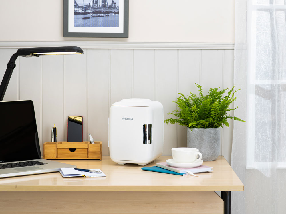 White mini fridge on desk with side handle.