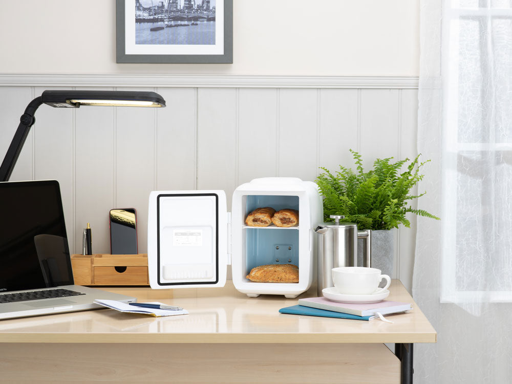 White mini fridge on a desk with door open and food items inside