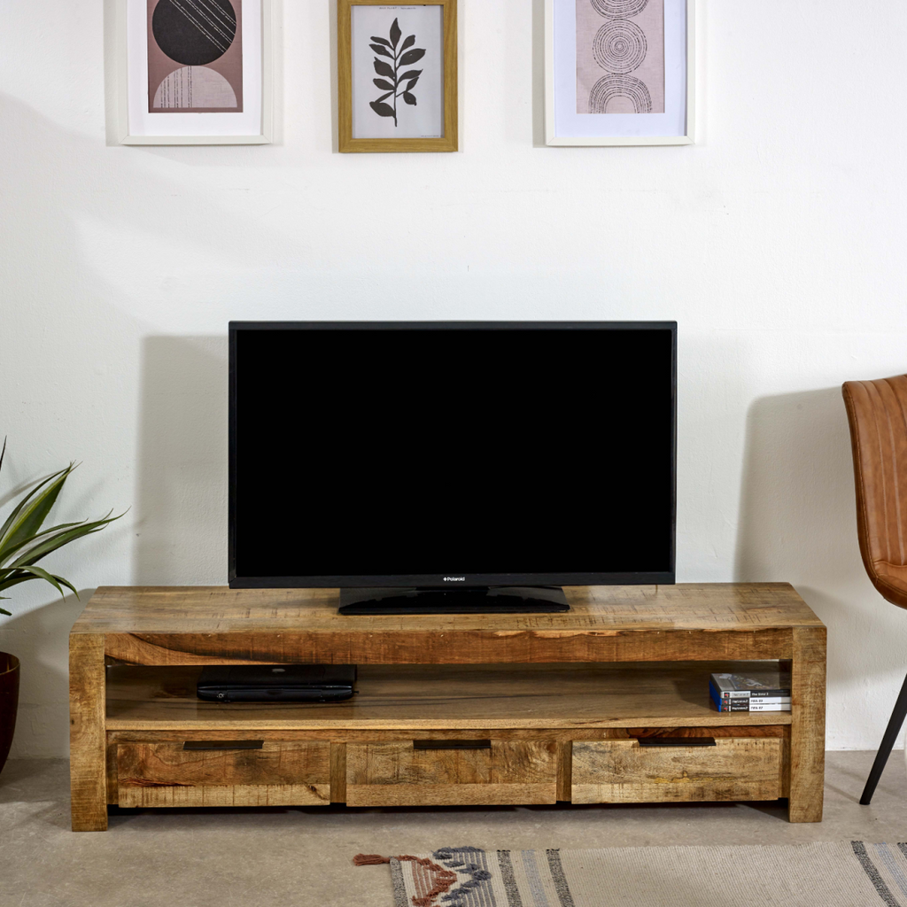 Wood TV media console with top shelf and three drawers; TV centered above storage.