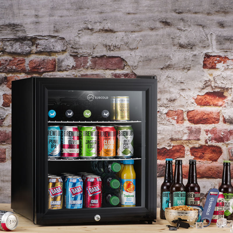 Subcold Super50 LED beer fridge, black open glass door with shelves of cans, bottles, and jars