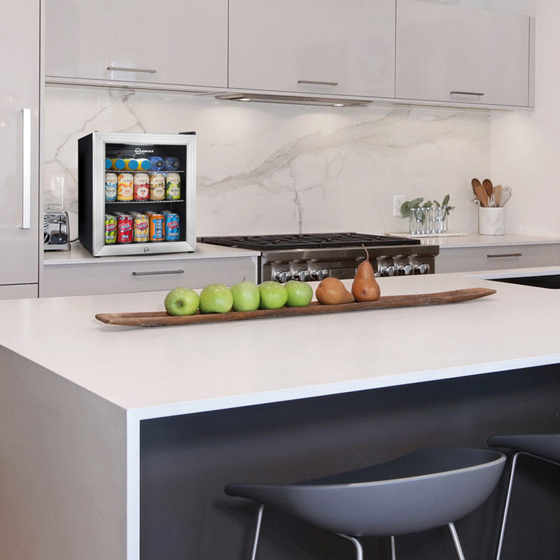 Mini black glass-door beverage fridge in a kitchen, with cans visible inside