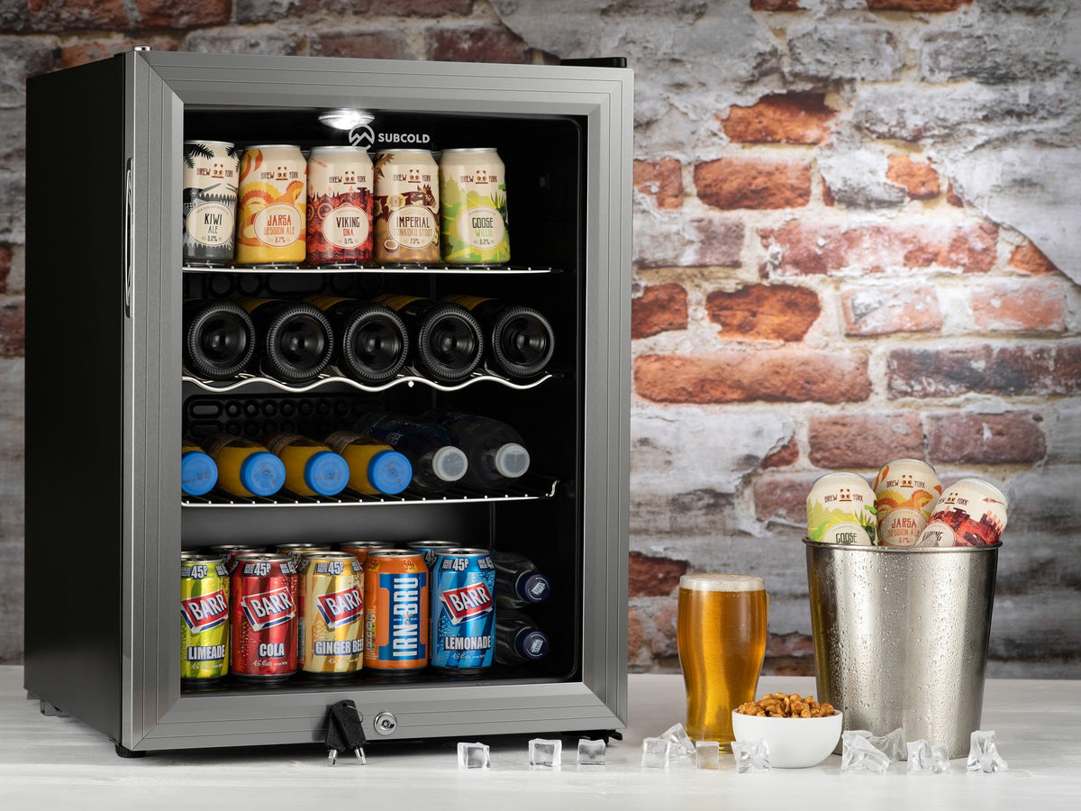 Silver drinks fridge open with beer bottles and can racks, illuminated interior