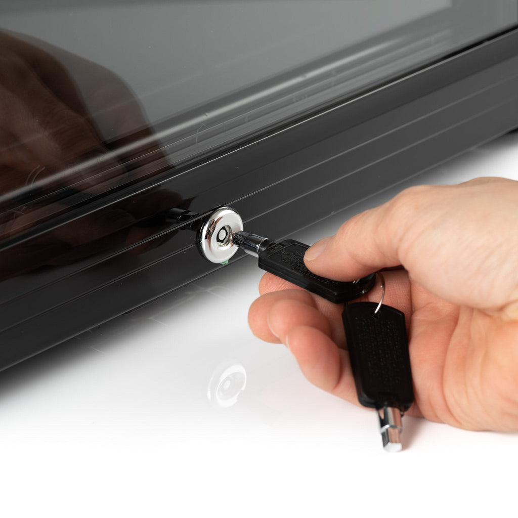 Dark drinks fridge door lock with key being inserted by hand
