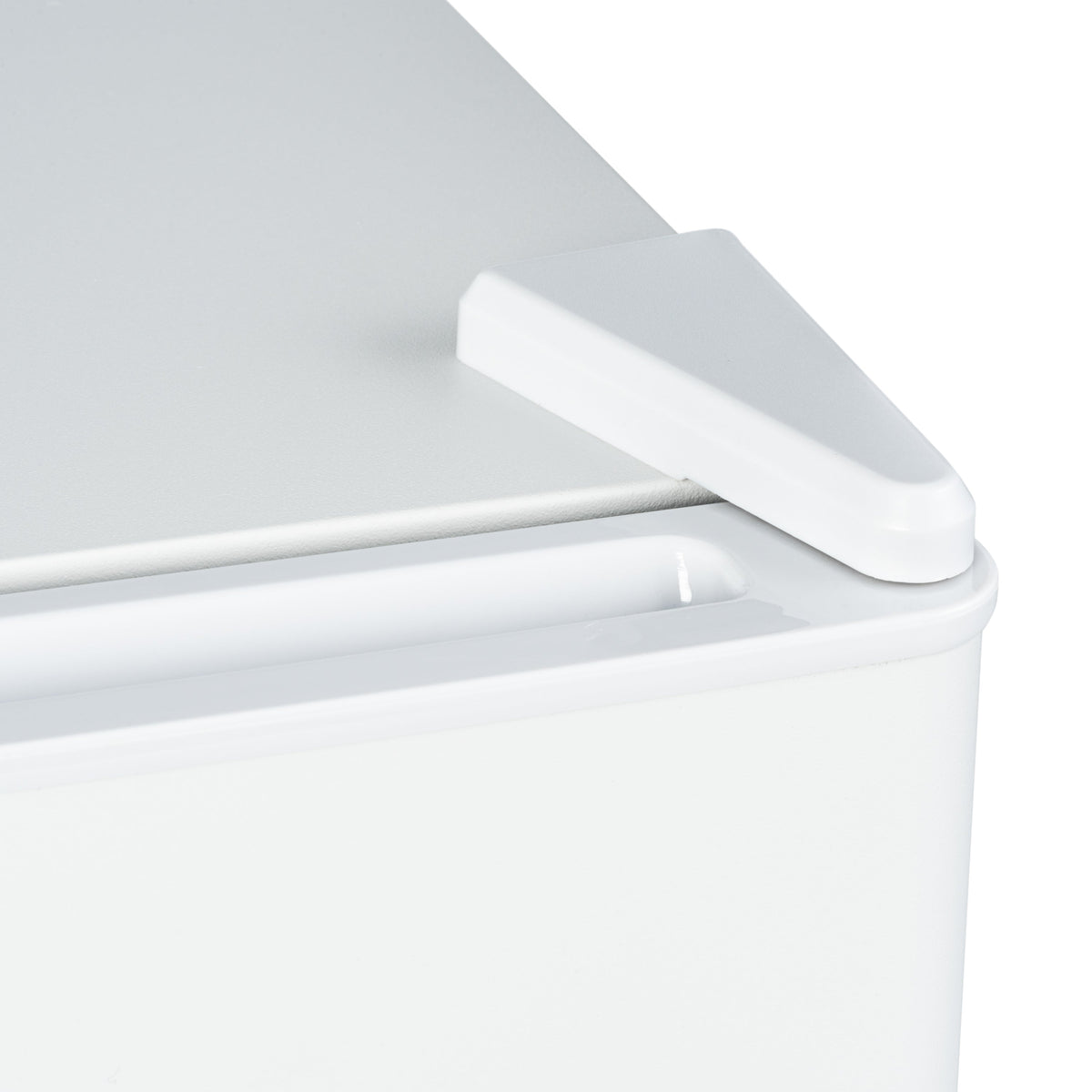 White mini fridge door handle and top edge close-up