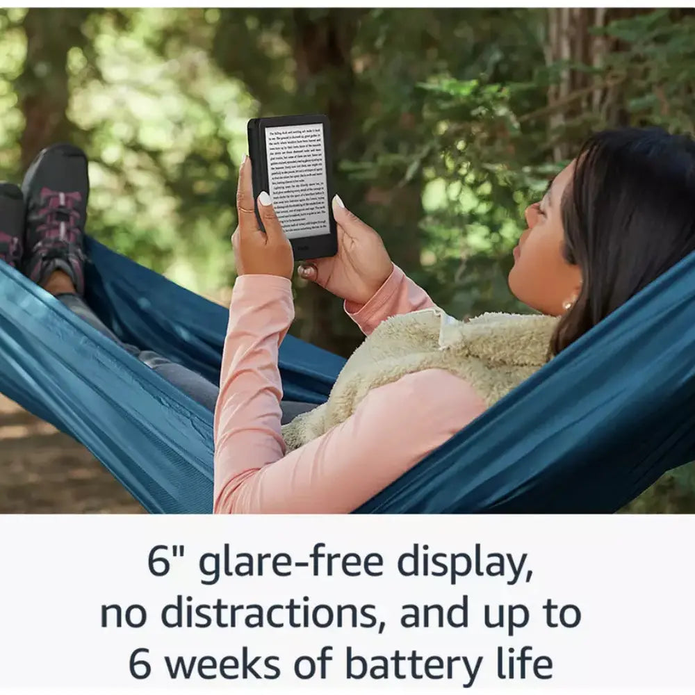 Black Kindle e-reader in hands at campsite, small book text on display