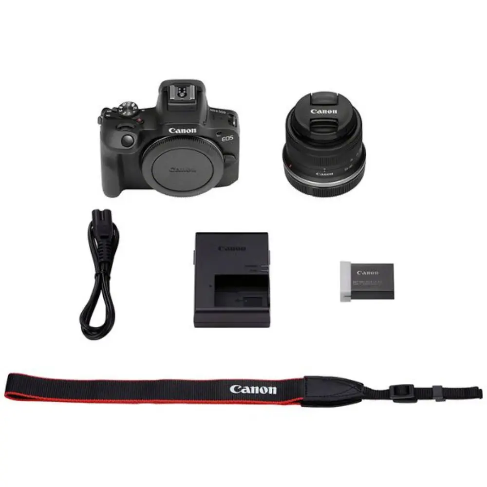 Digital camera kit showing camera body, lens, charger, strap, battery, and cable