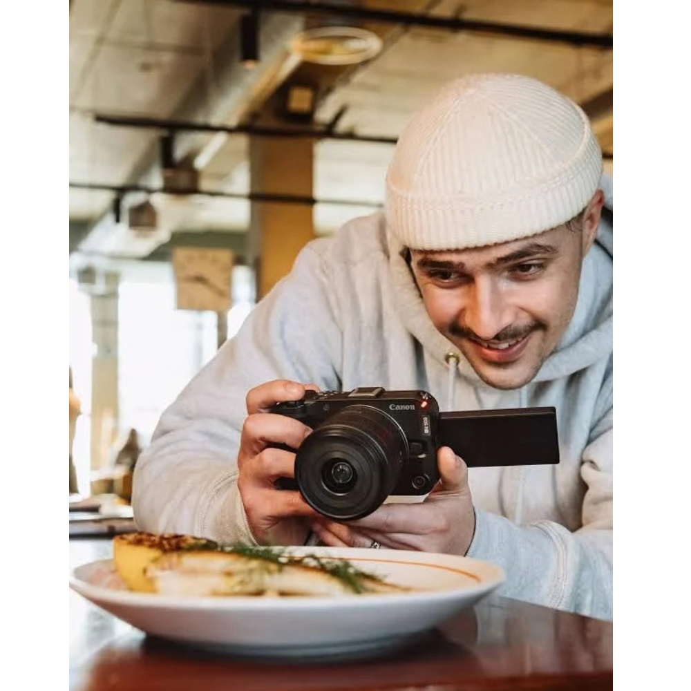 Canon mirrorless camera held by a person, lens facing forward