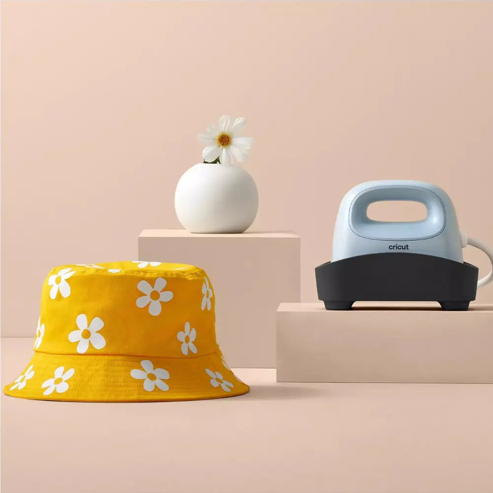 Cricut Hat Press next to yellow daisy bucket hat and white vase