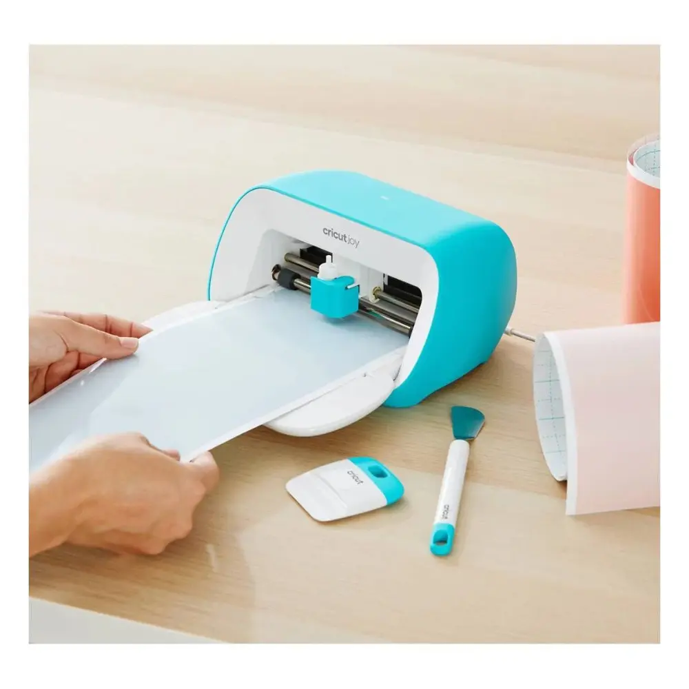 Tool set with teal cutting machine, blue accessory tools, and white scraper on desk