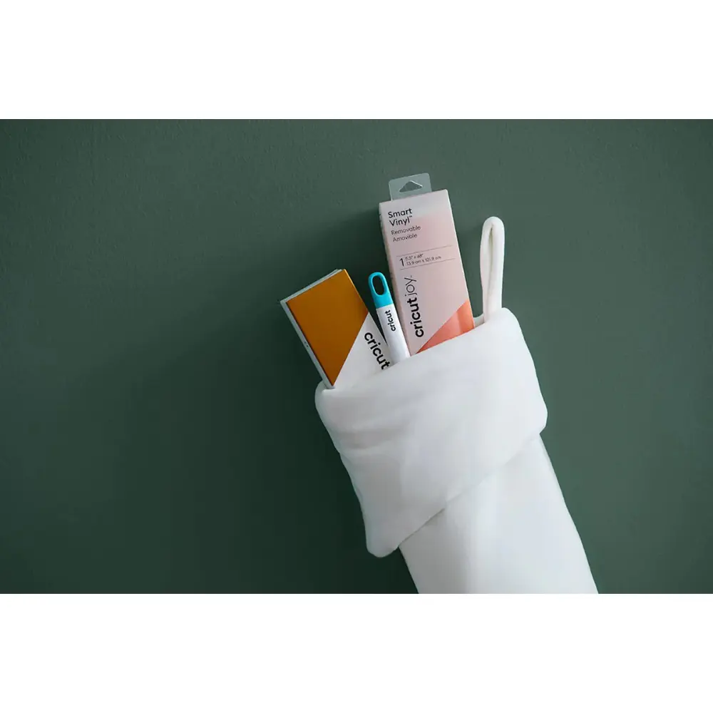 White-gloved hand holding Cricut tool insert and labeled card on green background