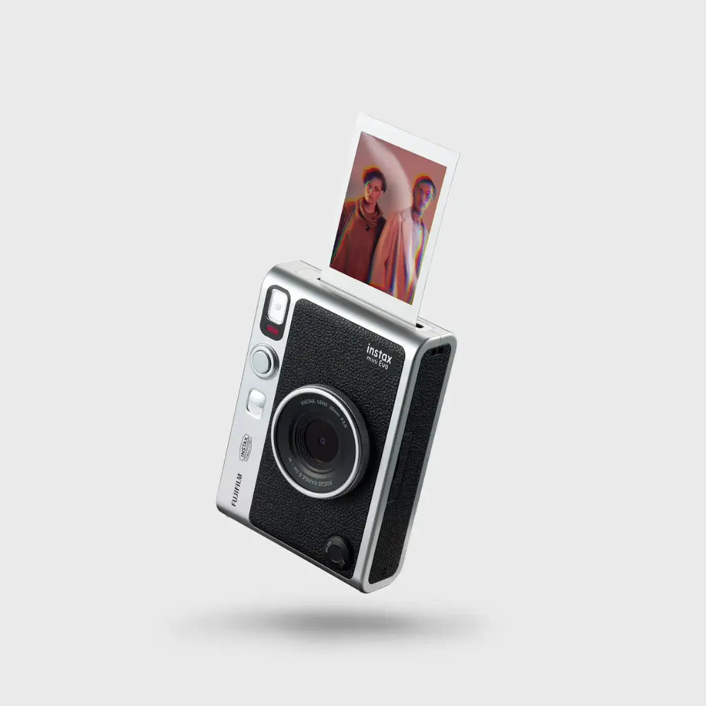 Hybrid instant camera with black textured front, silver body, lens and open photo print