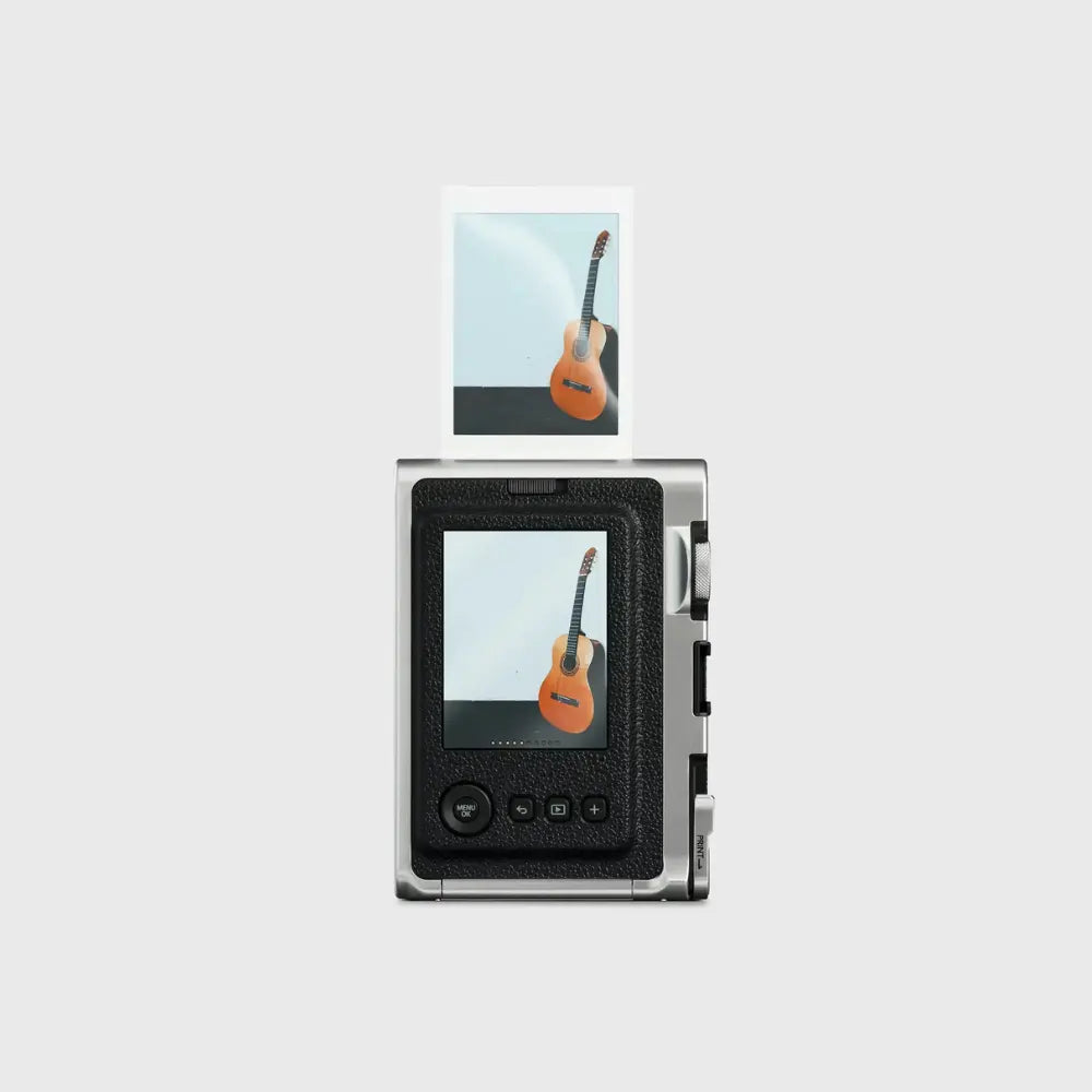 Hybrid instant camera front with black textured panel, lens, and photo print in window