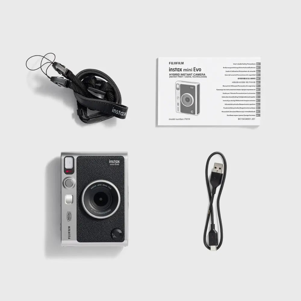 Hybrid instant camera with strap, charging cable, and instruction booklet