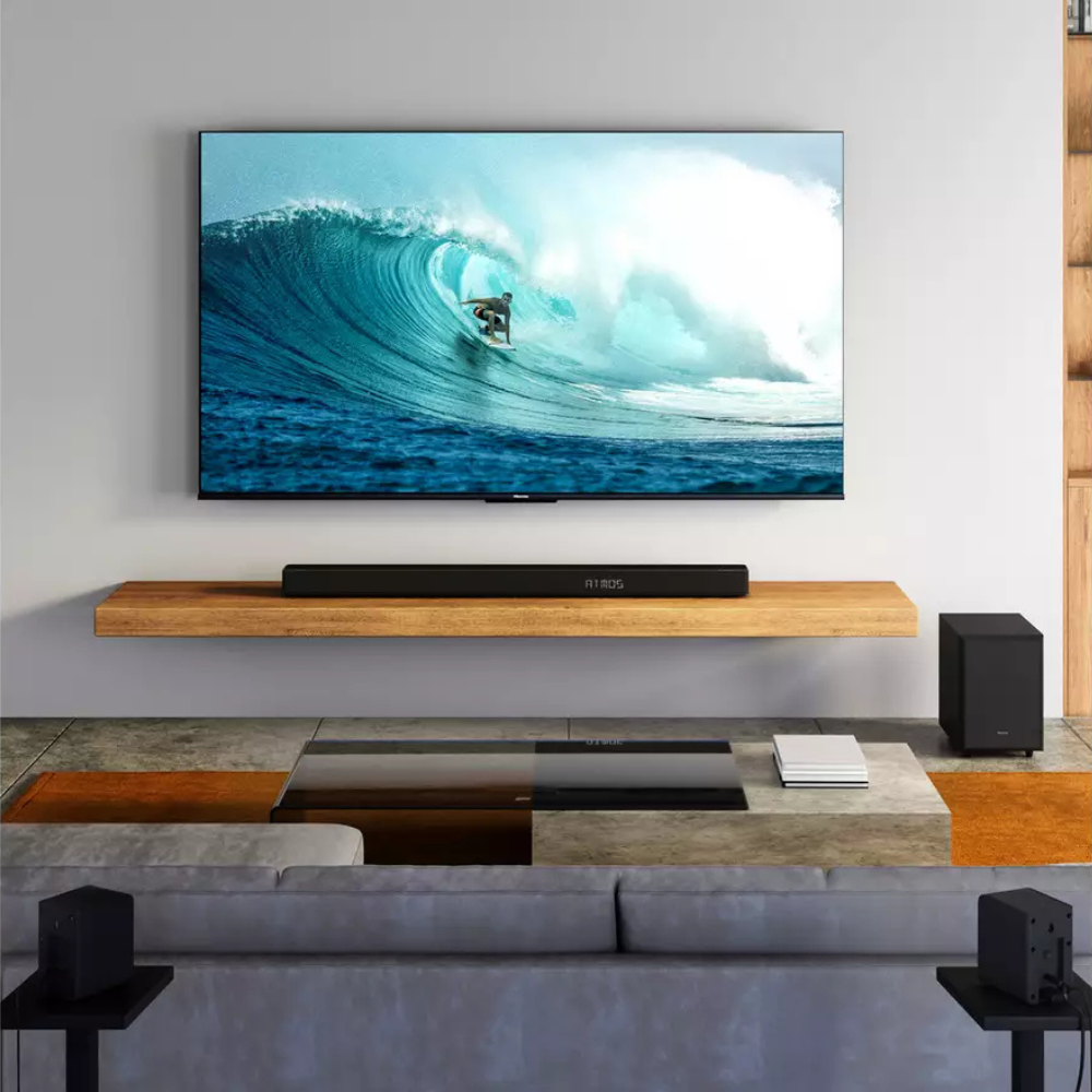 Black soundbar with subwoofer and wireless rear speakers arranged in a living room
