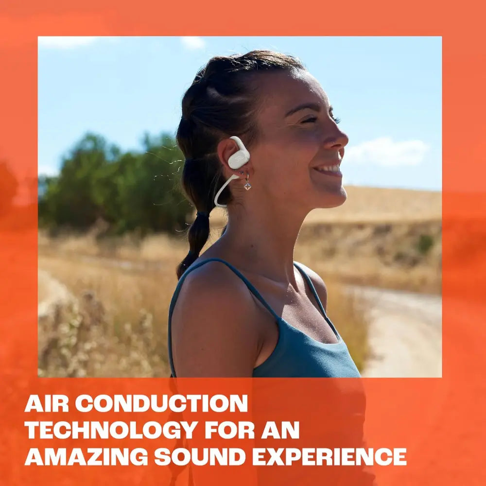 White wireless open-ear earbuds worn in one ear by a woman outdoors