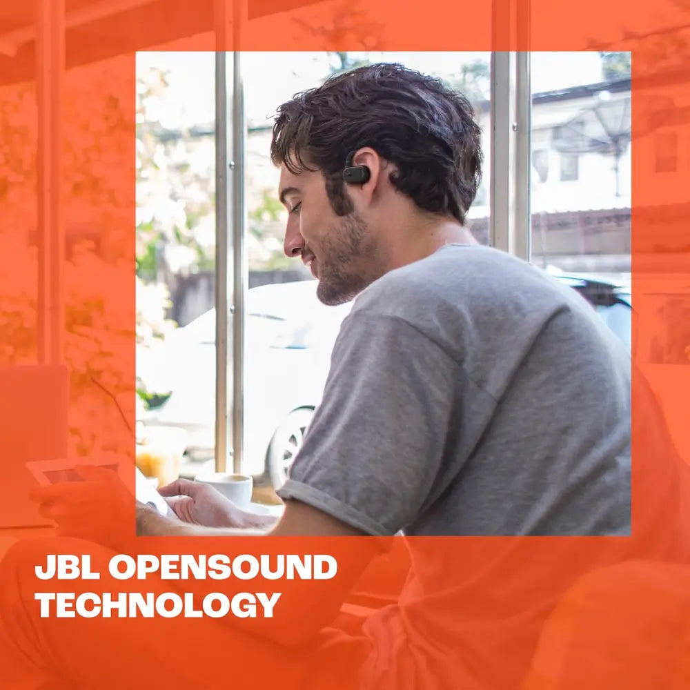 Black wireless open-ear earbuds worn by a man at a table