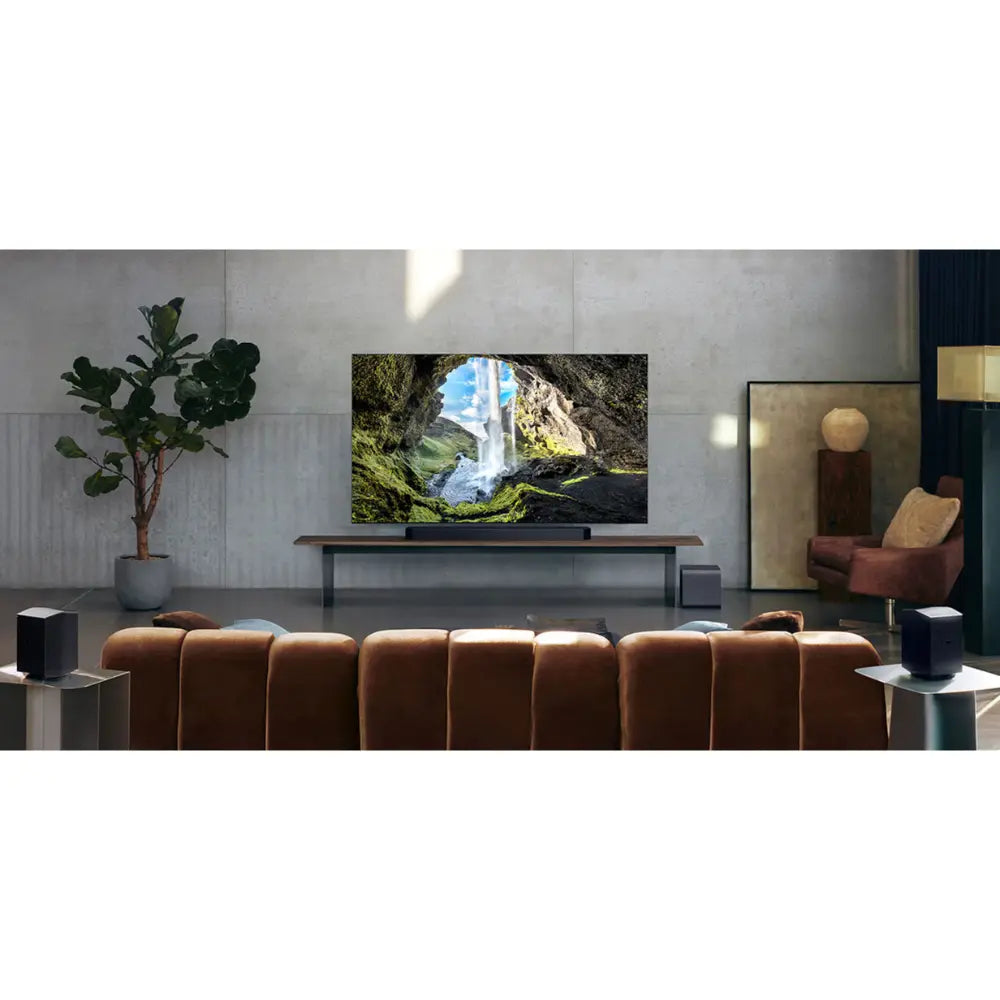 Black soundbar with two rear speakers in front of a TV