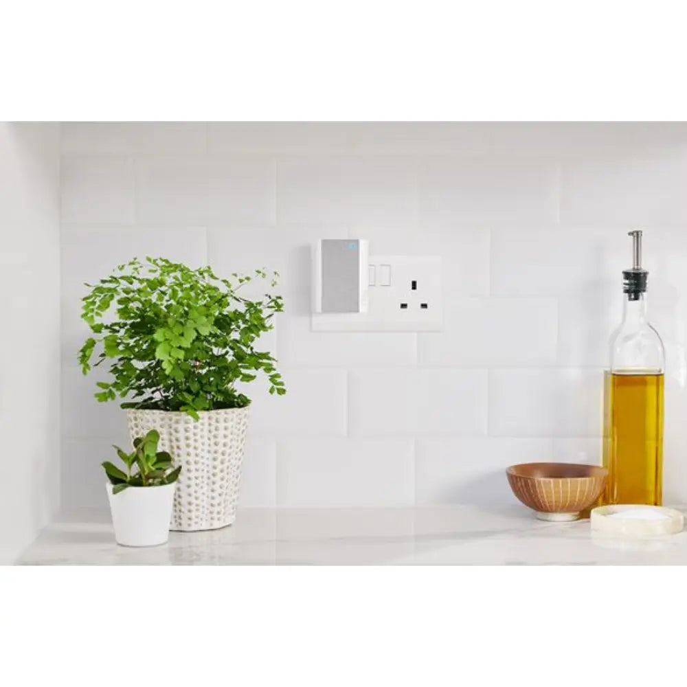 Wall-mounted smart chime on a white wall near an electrical outlet