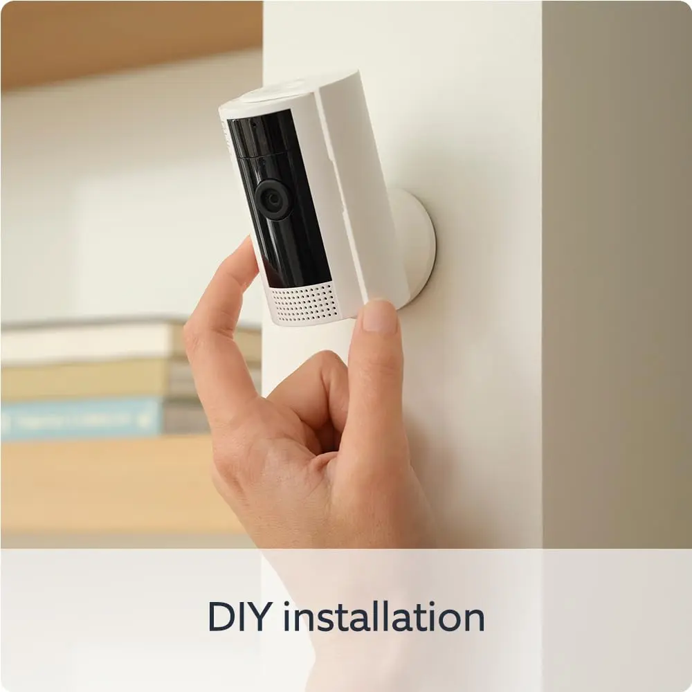 Indoor security camera being mounted on a wall, white housing, hands installing