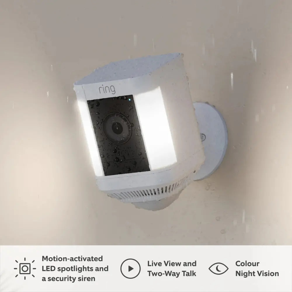 Ring Spotlight Cam Plus plug-in outdoor security camera in white on exterior wall, raindrops