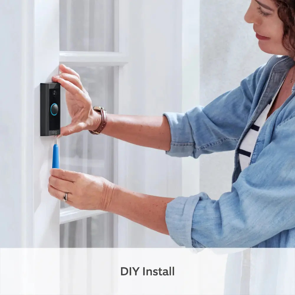 Wired video doorbell during DIY installation with hands attaching to doorframe