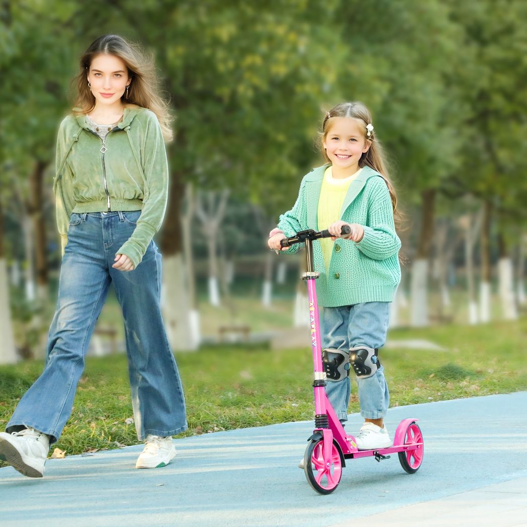 Pink kids kick scooter with front and rear wheels, ridden by a child
