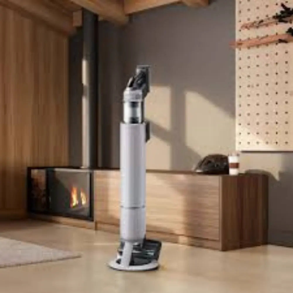 Cordless stick vacuum cleaner standing on round base, gray tube and black handle