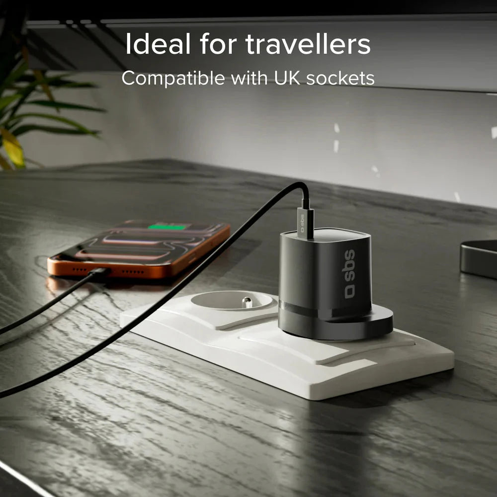 Black USB-C wall charger with UK 3-pin plug charging a phone