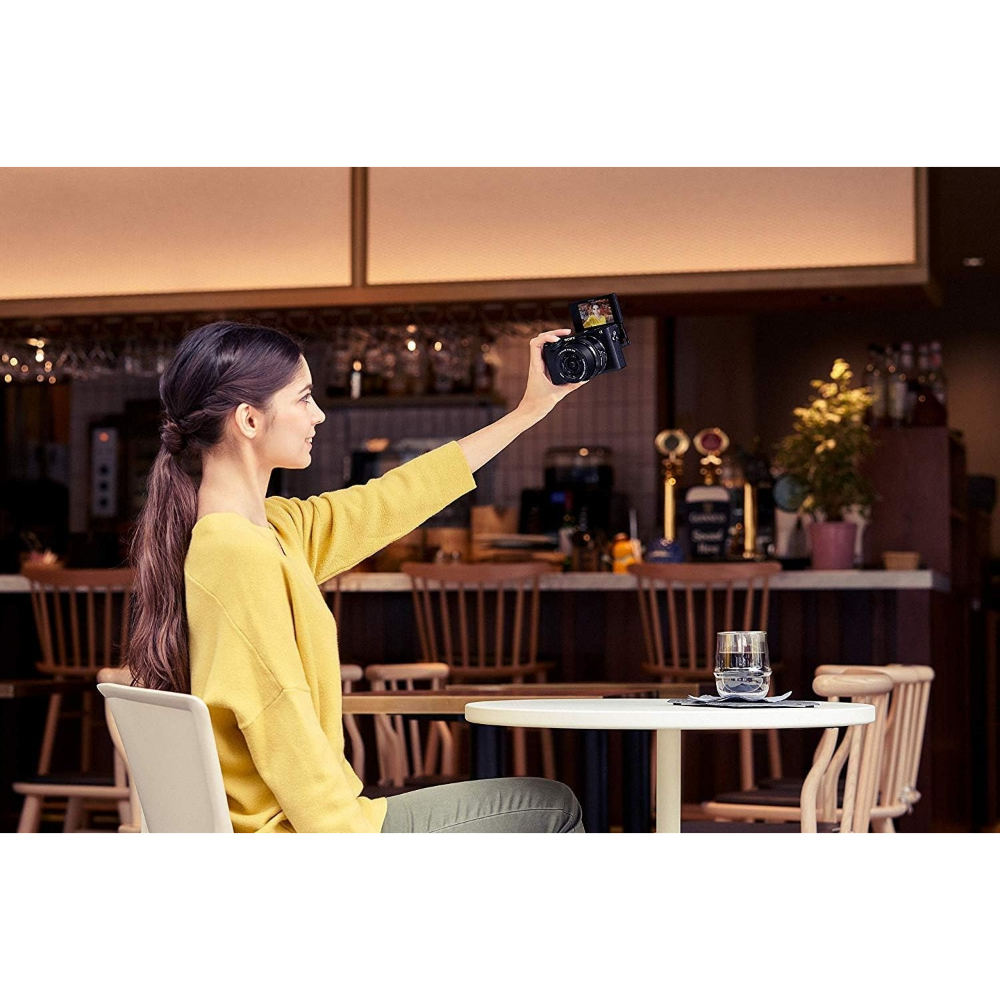 Handheld black mirrorless camera with 16-50mm lens raised to shoot