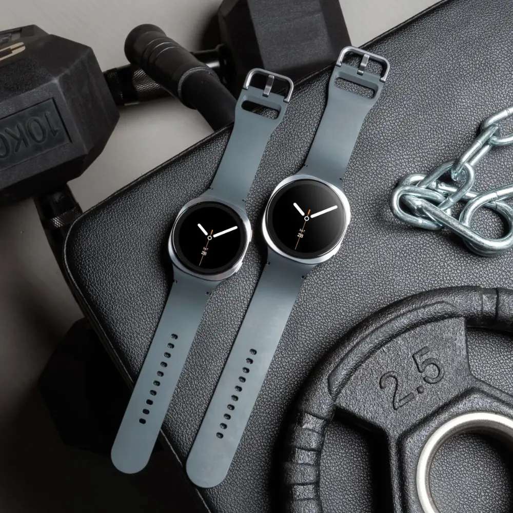 Two graphite smartwatches on textured surface, black faces and perforated silicone straps