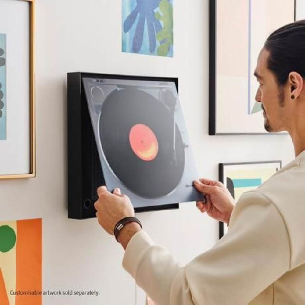 Black music frame speaker being mounted on a wall by hands