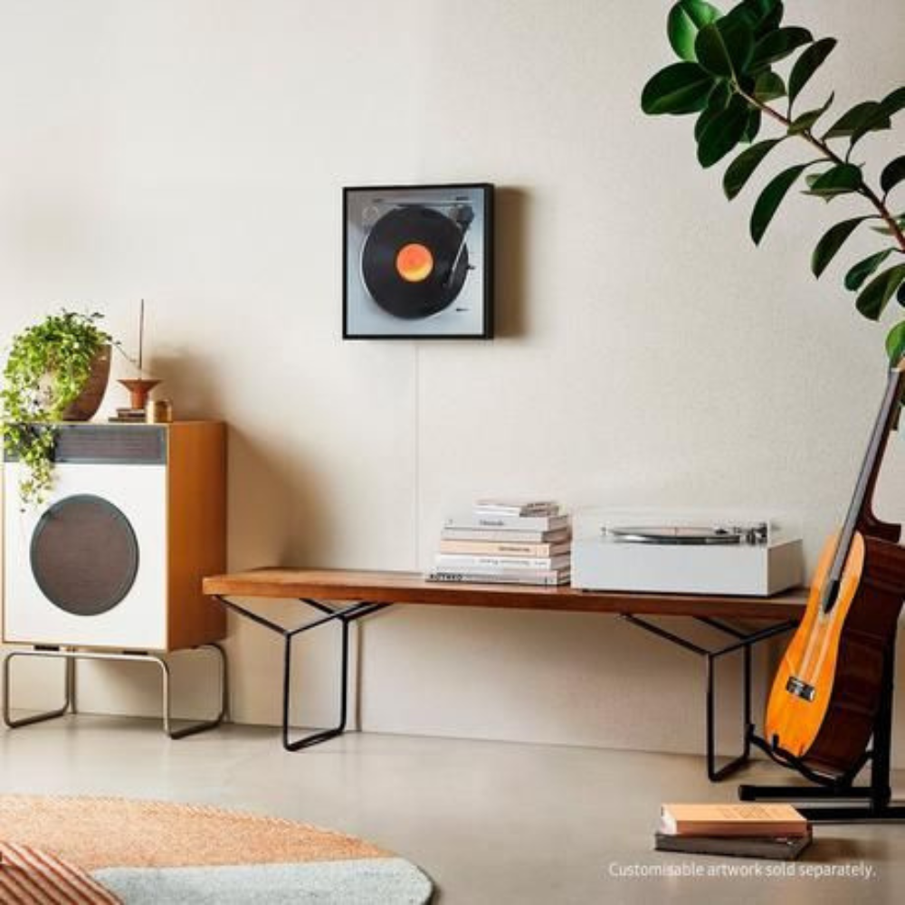 Black music frame wireless speaker on wall above a media console