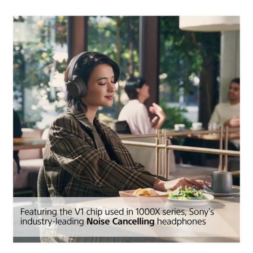 Wireless noise-cancelling over-ear Bluetooth headphones, dark finish, worn in cafe