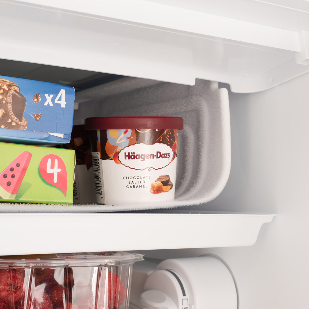 Under-counter LED fridge interior close-up with jars inside the lower storage tray