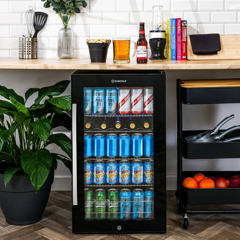 Black under-counter beer fridge with glass door, LED-lit shelves with assorted cans