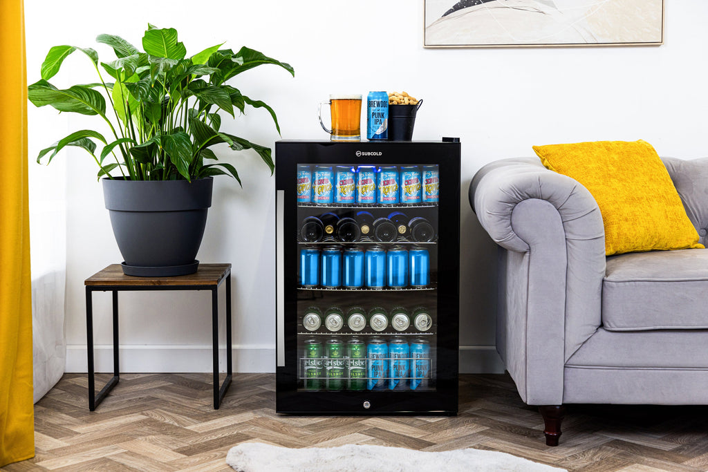 Black freestanding beer fridge with glass door, LED-lit interior, open living room setting