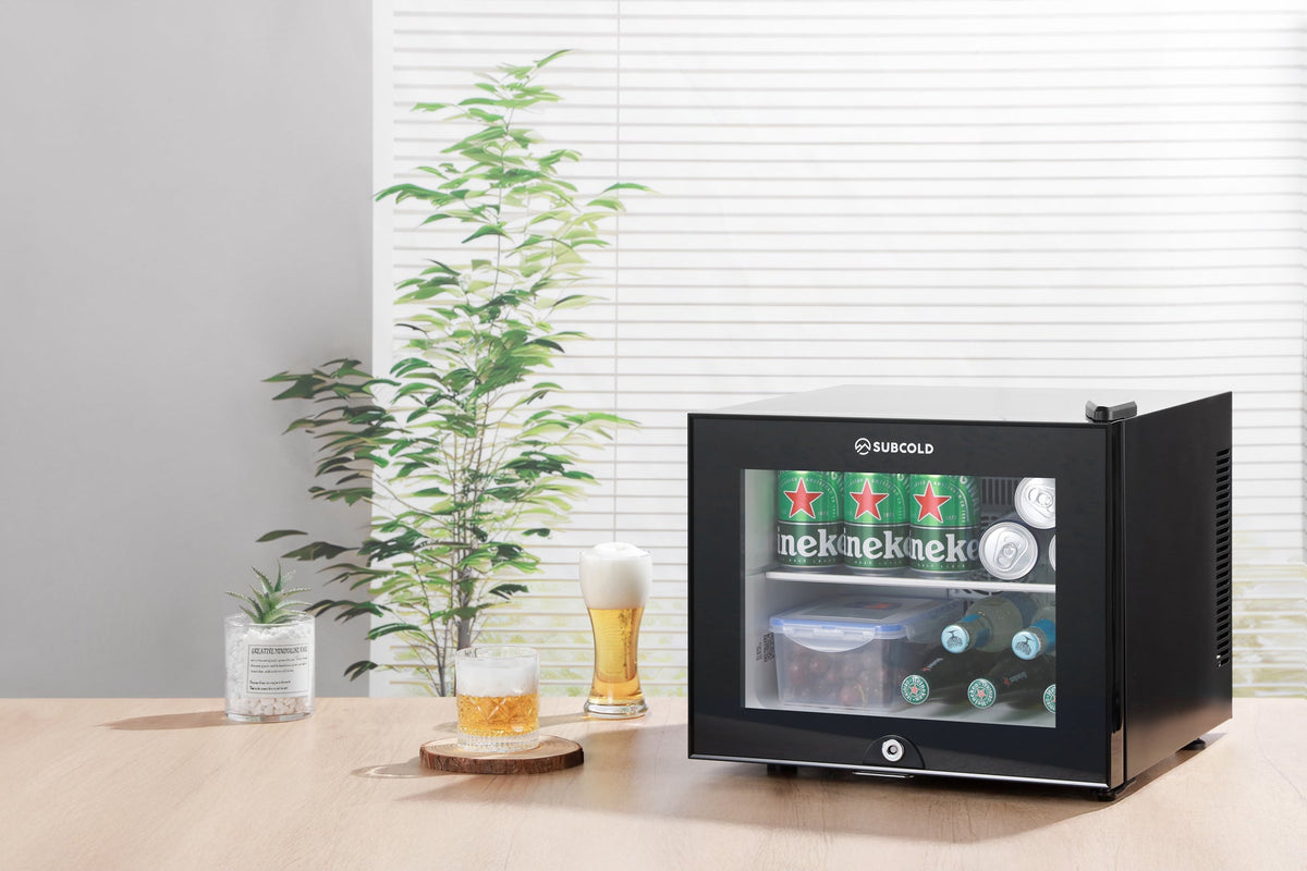 Black mini fridge with door closed and glass window revealing drinks inside