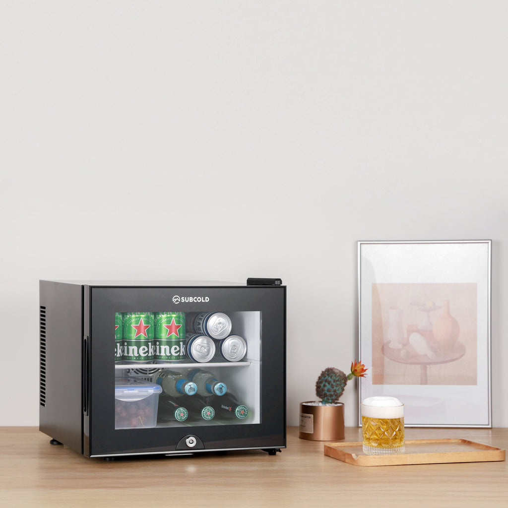 Black mini fridge on tabletop with closed door and lit window