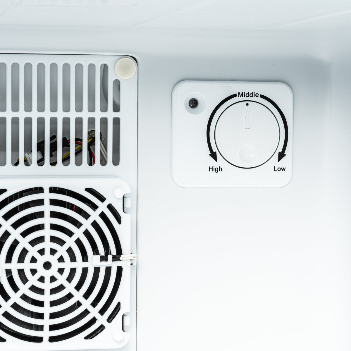 Mini fridge control dial marked High to Low and vent grille on left wall
