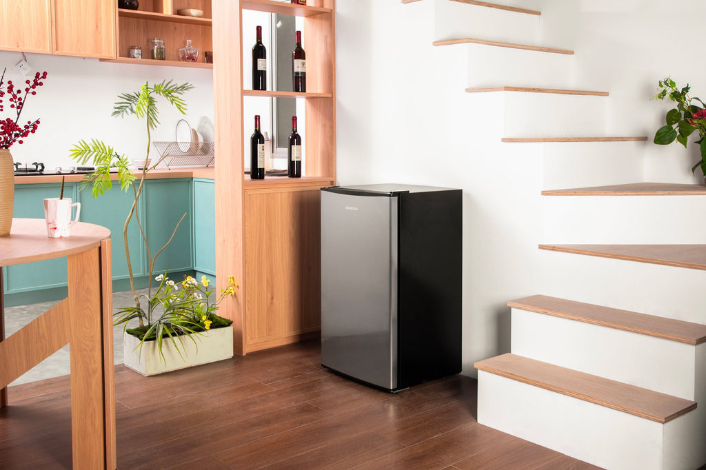 Black compact beer fridge with solid door standing in a room