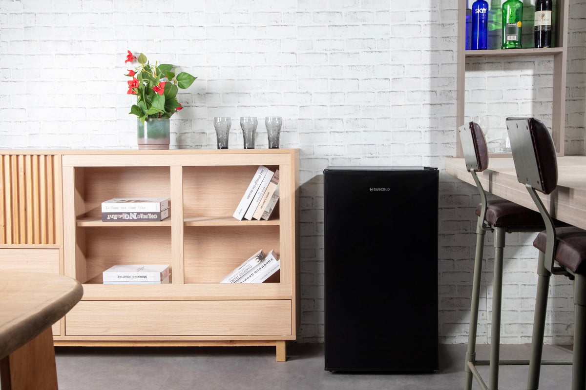Black compact beer fridge with solid door in a kitchen setting