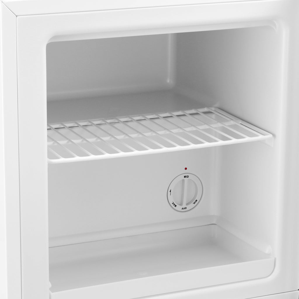 Mini freezer interior with wire shelf and round temperature dial on back wall