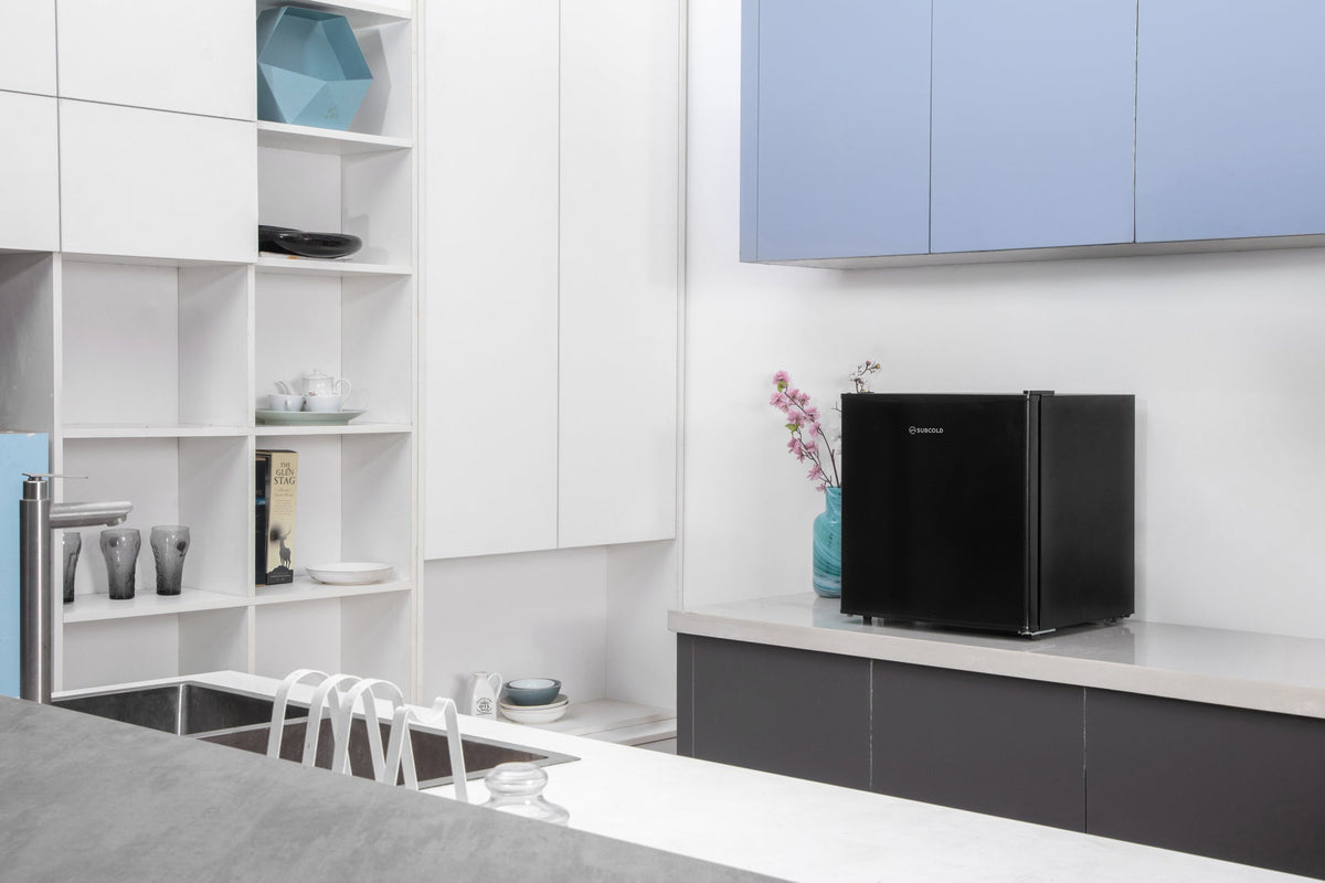 Black mini freezer on a countertop with cabinet storage around it